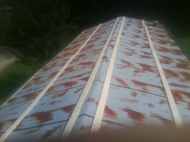 Rusted metal roof panels with new wood purlins before replacement — Storm Damage Roof Repair in Strawberry Point by Roofing Brothers