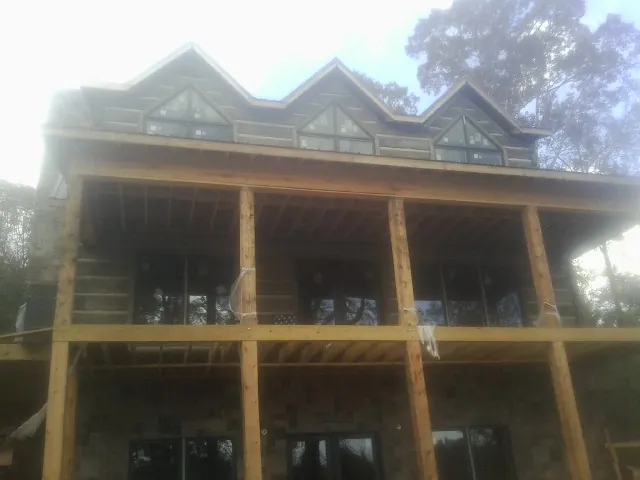 Dormers and porch framing on a large log home under construction — Roof Coating work by our crew in Strawberry Point