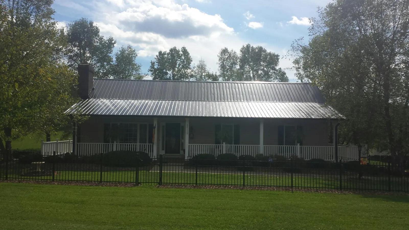 Gray metal roof on a brick ranch with a full width front porch — Gutter Guard Installation work by our crew in Strawberry Point