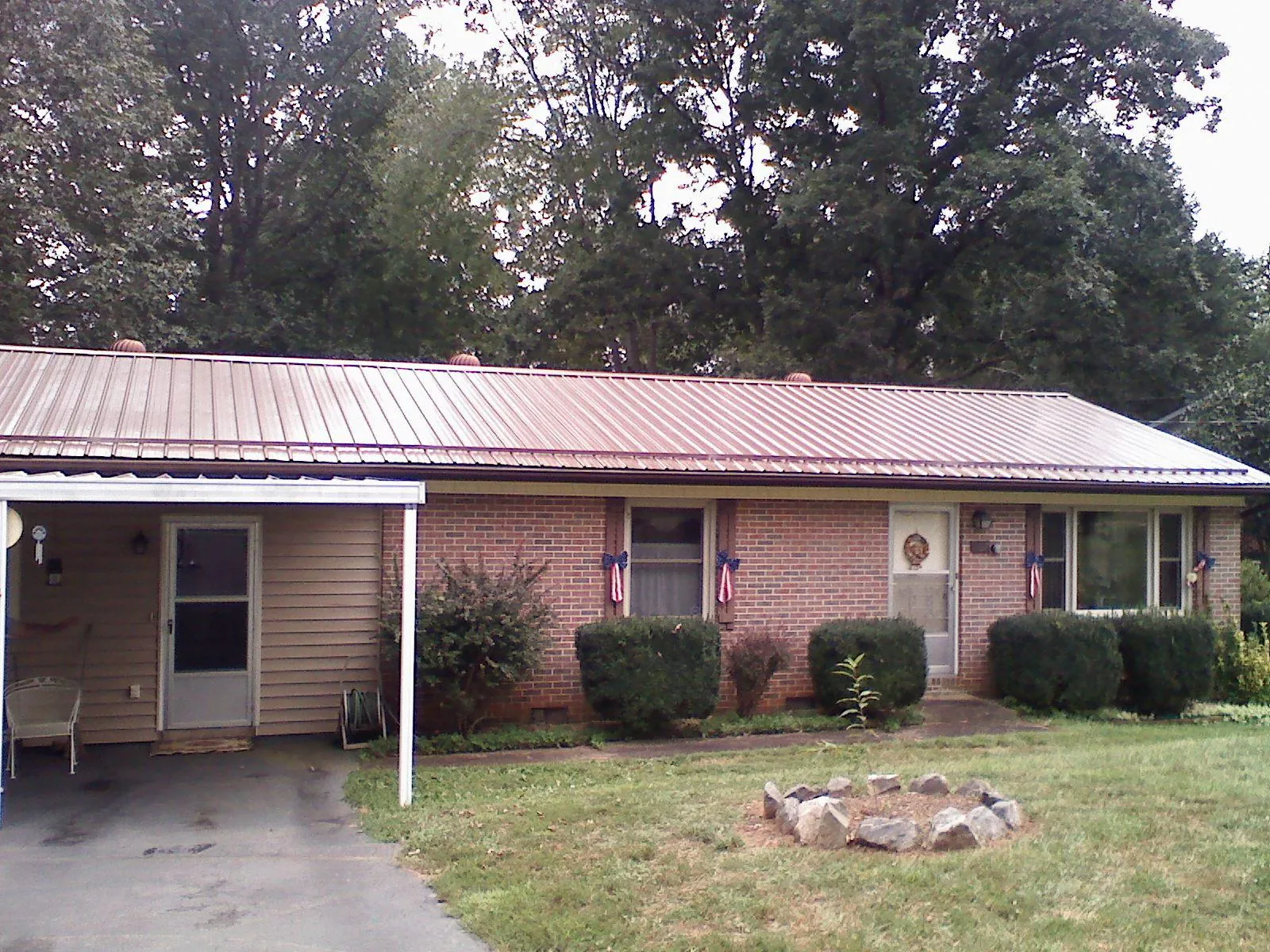 Bronze metal roof and carport on a brick ranch home — Roof Repair work by our crew in Strawberry Point